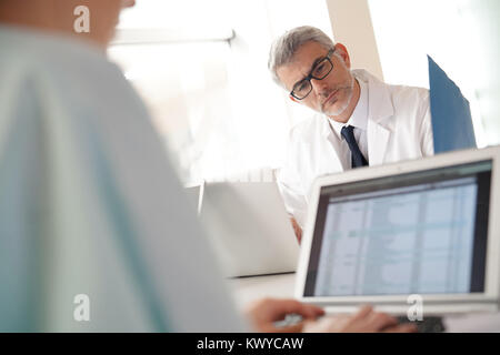 Mature doctor in office working on laptop computer Stock Photo