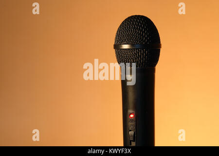 A modern black handheld ball head microphone on ginger background with copy space Stock Photo