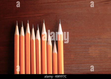 Few pencils standing in a row on dark wooden background with copy space Stock Photo