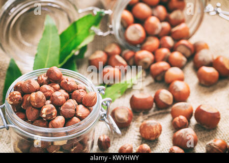 Peeled hazelnuts and hazelnuts in shell on a a burlap Stock Photo