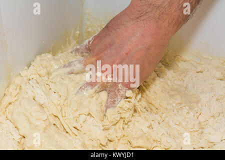 the chef's hands knead the dough to make pizza in the kitchen. Food, italian cuisine and cooking concept. Preparation of the Italian Pizza. Stock Photo