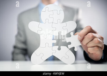 Businessman assembling jigsaw puzzle human team employee concept Stock Photo