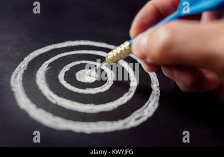 Businessman target for success holding dart on blackboard Stock Photo