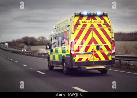 British ambulance responding to an emergency in hazardous bad weather driving conditions on a UK motorway Stock Photo