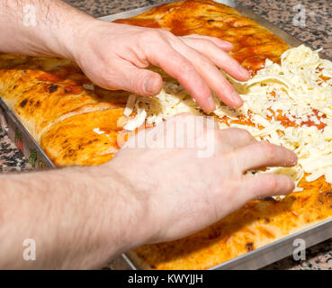 Fresh original Italian raw pizza focaccia, dough preparation in traditional style: the chef distributes the cheese. Food, italian cuisine and cooking  Stock Photo