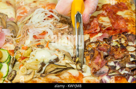 Closeup hand of chef baker cutting pizza focaccia at kitchen. Food, italian cuisine and cooking concept. Stock Photo