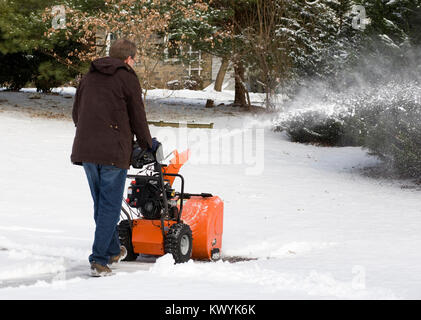 A man clearing the snow using a home snow blower. Stock Photo