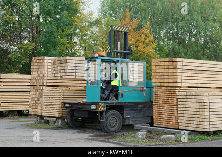 Green forklift transports the boards at the plant for woodworking. Woodworking industry Stock Photo