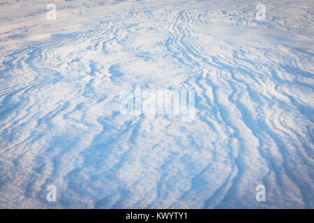 Abstract wind patterns on fresh snow in light of sunrising sun Stock Photo
