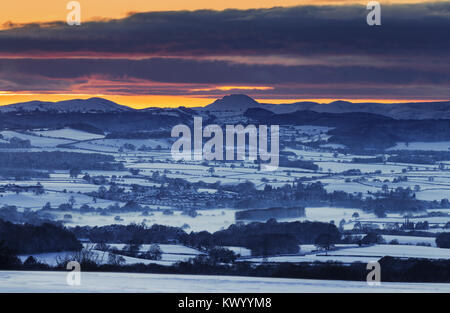 Dramatic sunset clouds over scenic hills covered in snow at winter. Shropshire Hills in United Kingdom Stock Photo