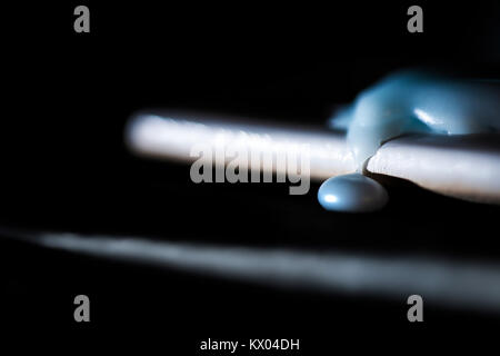 Broken melted cold wax on black texture. Stock Photo
