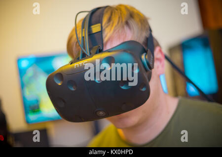Young man wearing a virtual reality headset and playing a VR game Stock Photo
