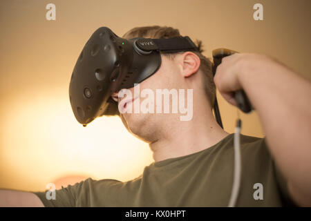 Young man wearing a virtual reality headset and playing a VR game Stock Photo