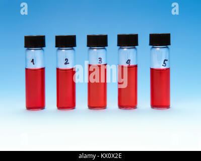 Red liquid samples in a transparent plastic tray on blue gradient background Stock Photo