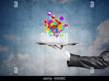 Closeup of waitress's hand in white glove presenting multiple cubes on metal tray with blue cloudy skyscape drawn on wall on the background. 3D render Stock Photo