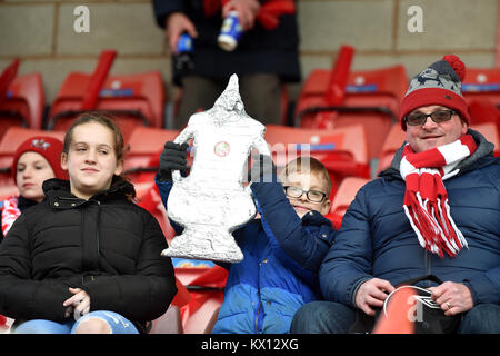 A young fan holds a tin foil FA cup in the stands prior to the FA Cup, third round match at St James' Park, Exeter. Stock Photo