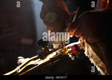 Man cleaning oxy acetylene torch propane tools for cutting metal in his workshop. Stock Photo