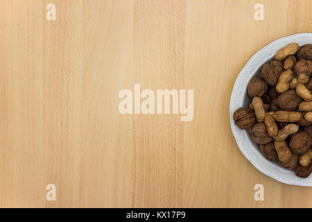 plate of nuts on wooden table, top view with empty space Stock Photo