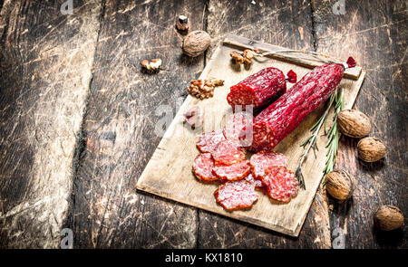 Salami with spices and nuts. On a wooden background. Stock Photo