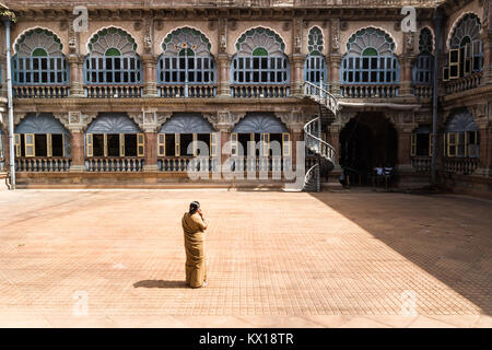 Mysore, India - December 10 2017: Yard in Mysore Palace with windows and arches in sunlight with female security Stock Photo