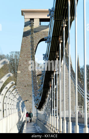 An Asian couple, man and woman, holding hands. taking a brisk winter stroll across the Clifton Suspension bridge, Bristol.Its a cold, sunny winter day Stock Photo