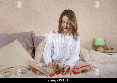 Girl in a white sweater wraps a gift Stock Photo