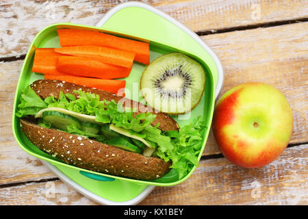 Healthy lunch box containing brown cheese sandwich, crunchy carrots, kiwi fruit and apple Stock Photo
