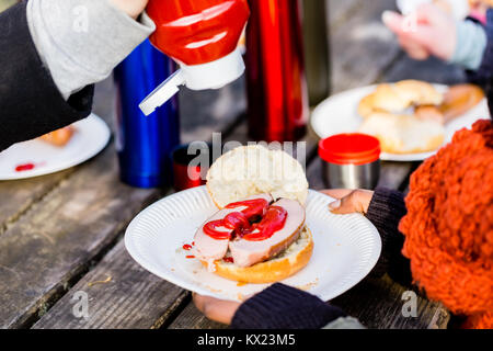 Roasted sausage with ketchup served outdoors at picnic table Stock Photo
