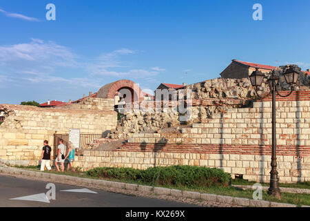 Nesebar, Bulgaria - July 20, 2014: Tourists walk near ruined tower and stone walls around Nesebar historic town Stock Photo