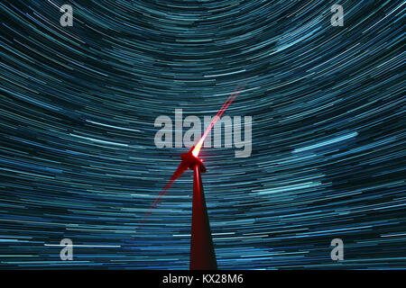 A wind turbine with a star trailed sky in the background Stock Photo