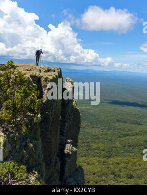 Wildlife photographer on mountain summit taking pictures of sunset in landscape and blue sky Stock Photo