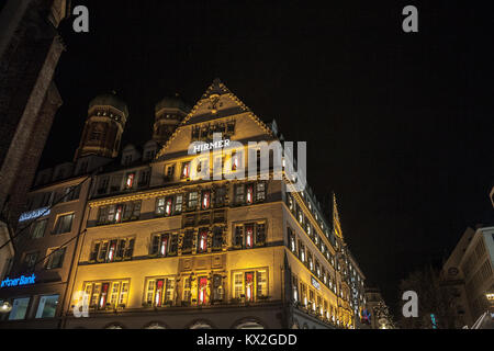 MUNICH, GERMANY - DECEMBER 17, 2017: Hirmer department store in a traditional Bavarian building in downtown Munich, Frauenkirche church can be seen in Stock Photo