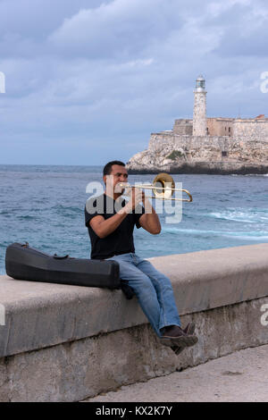 Musician playing the trumpet sitting on the Malecon wall, in Havana, Cuba Stock Photo