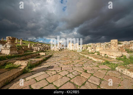 A Roman road in the ancient city of Gerasa after a storm with dark grey clouds Stock Photo