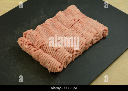 Raw ground turkey meat on black cutting board on wooden table Stock Photo