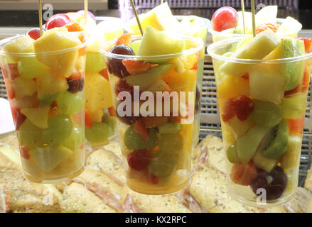 many glasses filled with fruit salad with pineapple cherry pears grapes apples Stock Photo