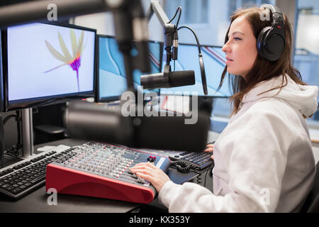 Host Using Headphones And Microphone While Looking At Monitor Stock Photo