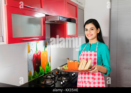 Portrait of A Lady Holding a Serving Tray In kitchen At-Home Stock Photo