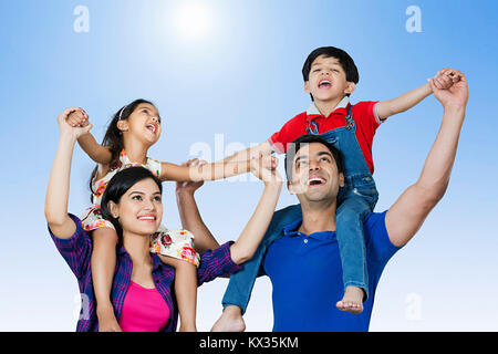 Happy Family Parents Carrying Children on shoulders Having fun Outdoors Stock Photo