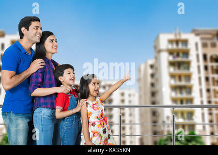 Happy Family- Parents And Children Pointing Finger Showing Balcony At-Home Stock Photo