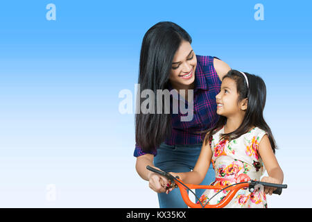 Smiling Mother Teaching Little Girl To Riding Bicycle Enjoying Park Stock Photo