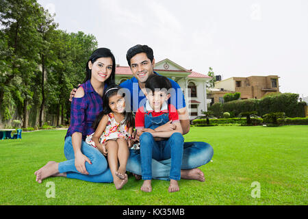 Happy Family Parents And Children Sitting Grass Together Outside Home Stock Photo