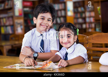 2 Indian School Kids Students Reading Book Studying In Library Stock Photo