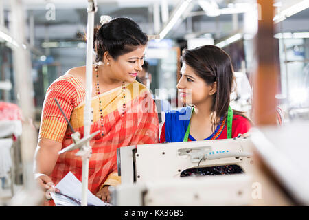 2 Ladies, Tailor And Manager Checking Papers In Sewing Factory Stock Photo