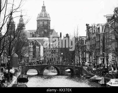 The Oudezijdsvoorburgwal  a street and canal in the Red-light district  in the center of Amsterdam. In the background The Basilica of St. Nicholas.  B Stock Photo