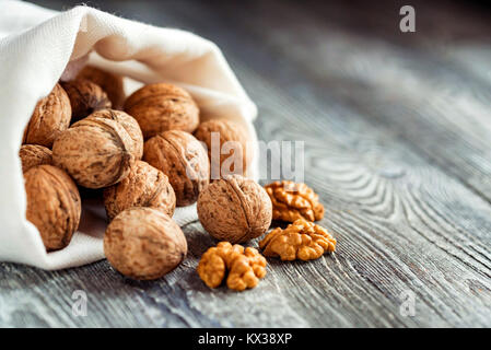 Walnuts in sack on wooden backgound Stock Photo