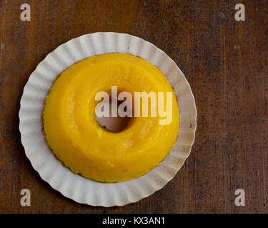 Closeup on quindim, a tasty yellow Brazilian dessert made with condensed milk and eggs on grunge wooden table, viewed from the top Stock Photo