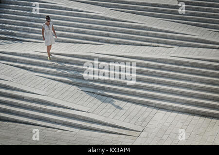 Woman in stripy dress walking down steps Stock Photo