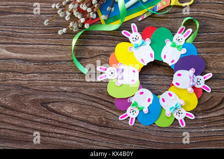 Children's Easter gift wreath with colorful eggs and Easter bunnies. Hand-made. Children's art project for children. Craft for kids. Flat lay. Top vie Stock Photo
