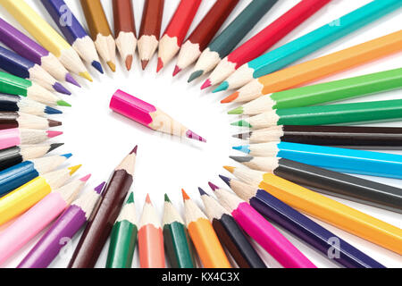 Little pink pencil in a circle of big pencils isolated on a white background Stock Photo
